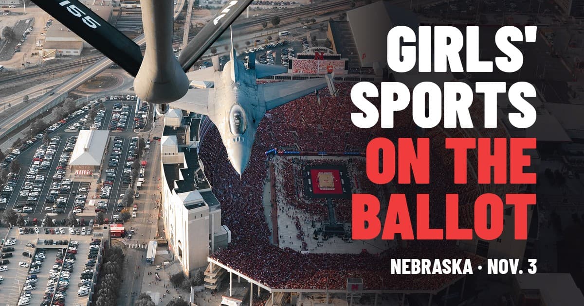 Vista aérea del Memorial Stadium en Lincoln, lleno durante el Nebraska Volleyball Day, con un KC-135 y un F-16 sobrevolando